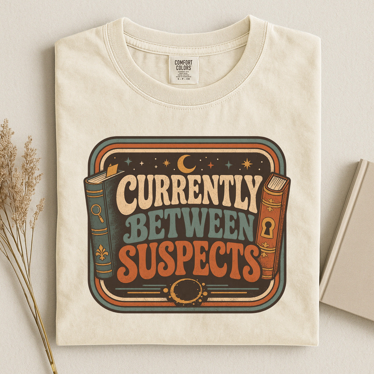 Shelf Love Studio Currently Between Suspects t-shirt in Ivory, styled flat lay