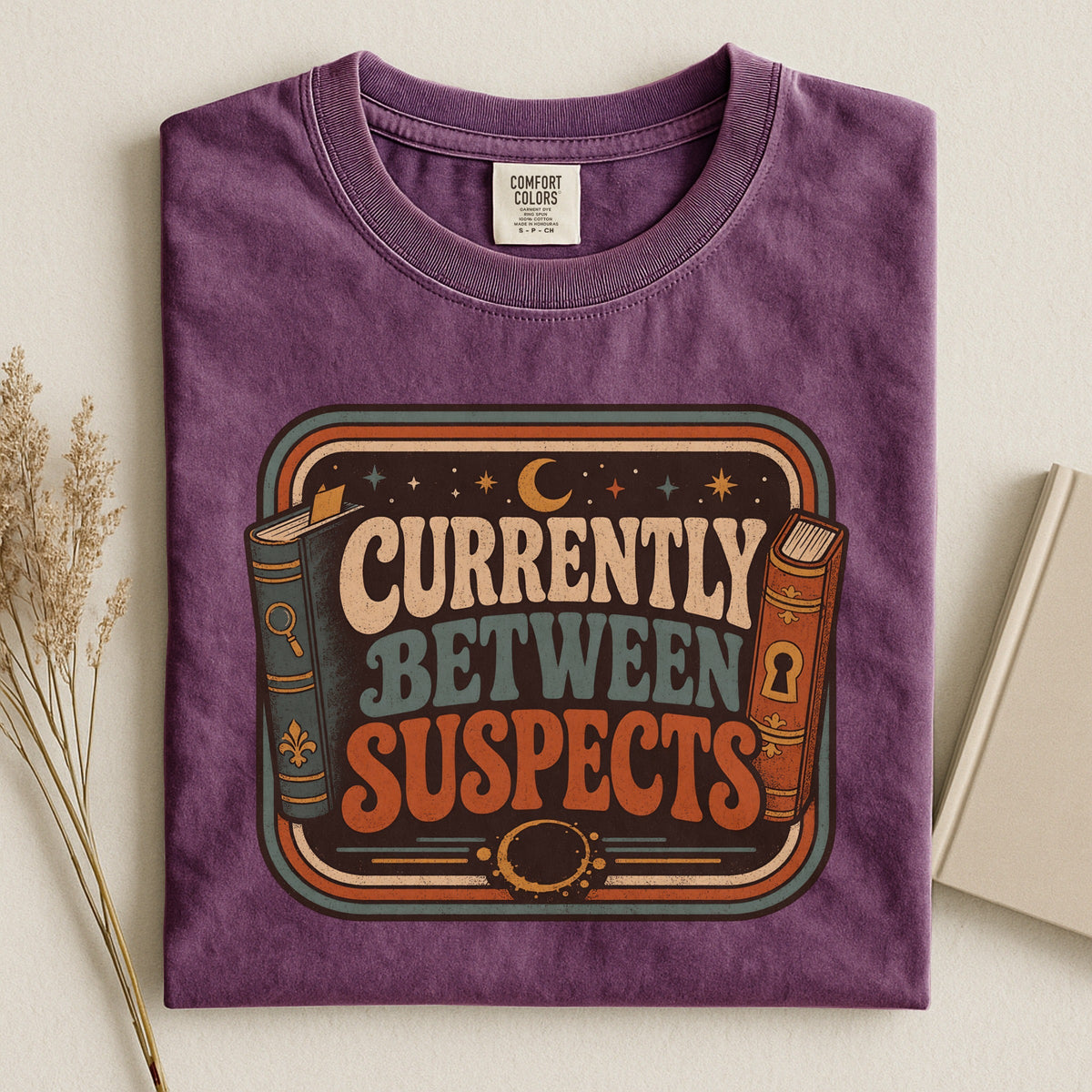 Shelf Love Studio Currently Between Suspects t-shirt in Berry, styled flat lay