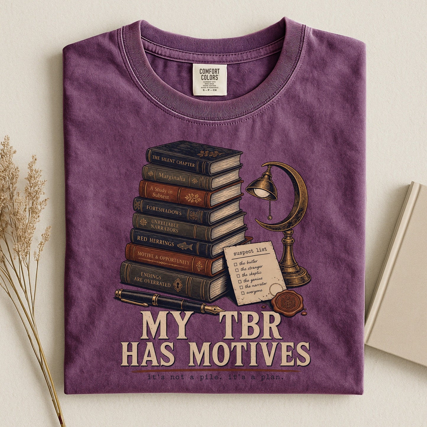 My TBR Has Motives bookish tee in Berry, flat lay