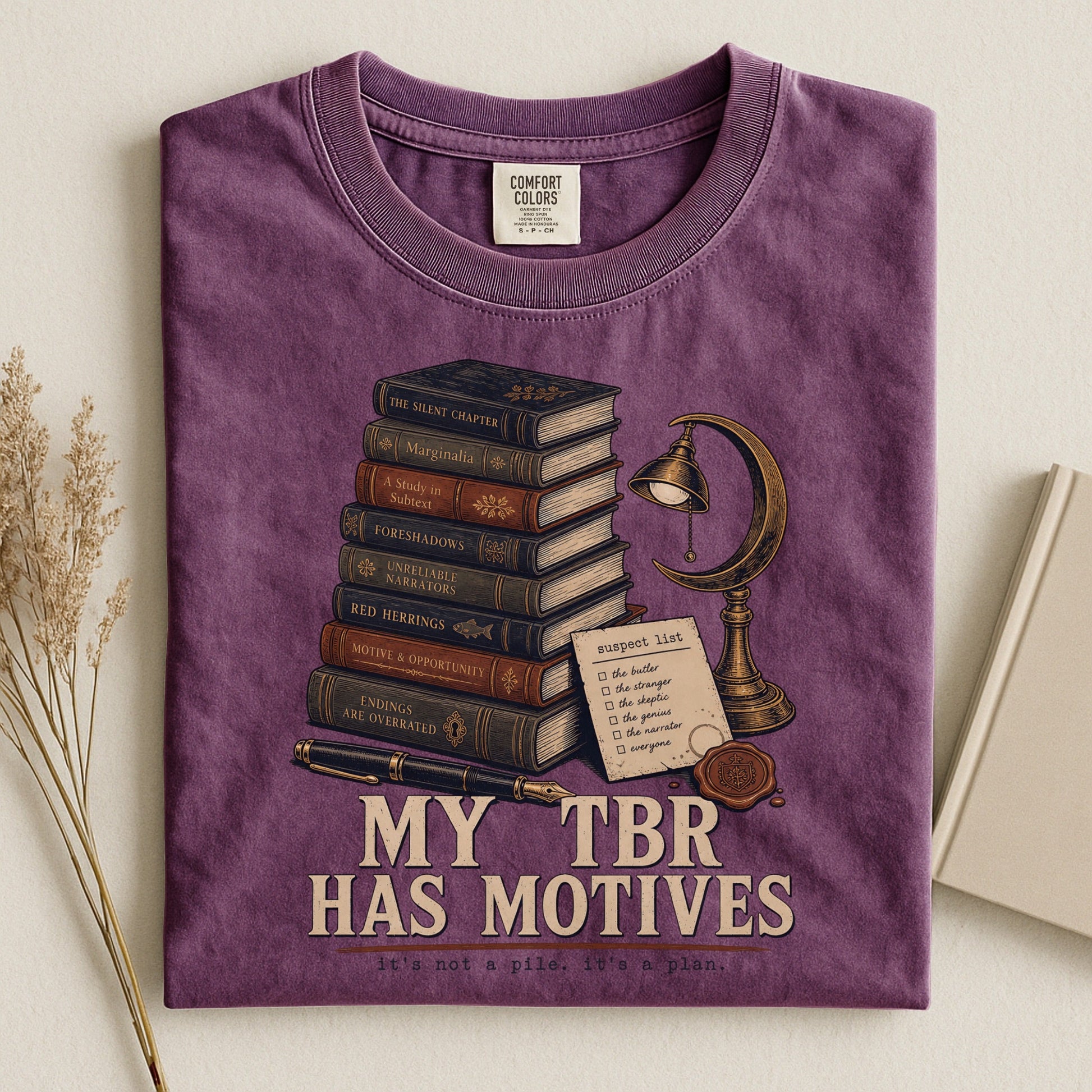 My TBR Has Motives bookish tee in Berry, flat lay