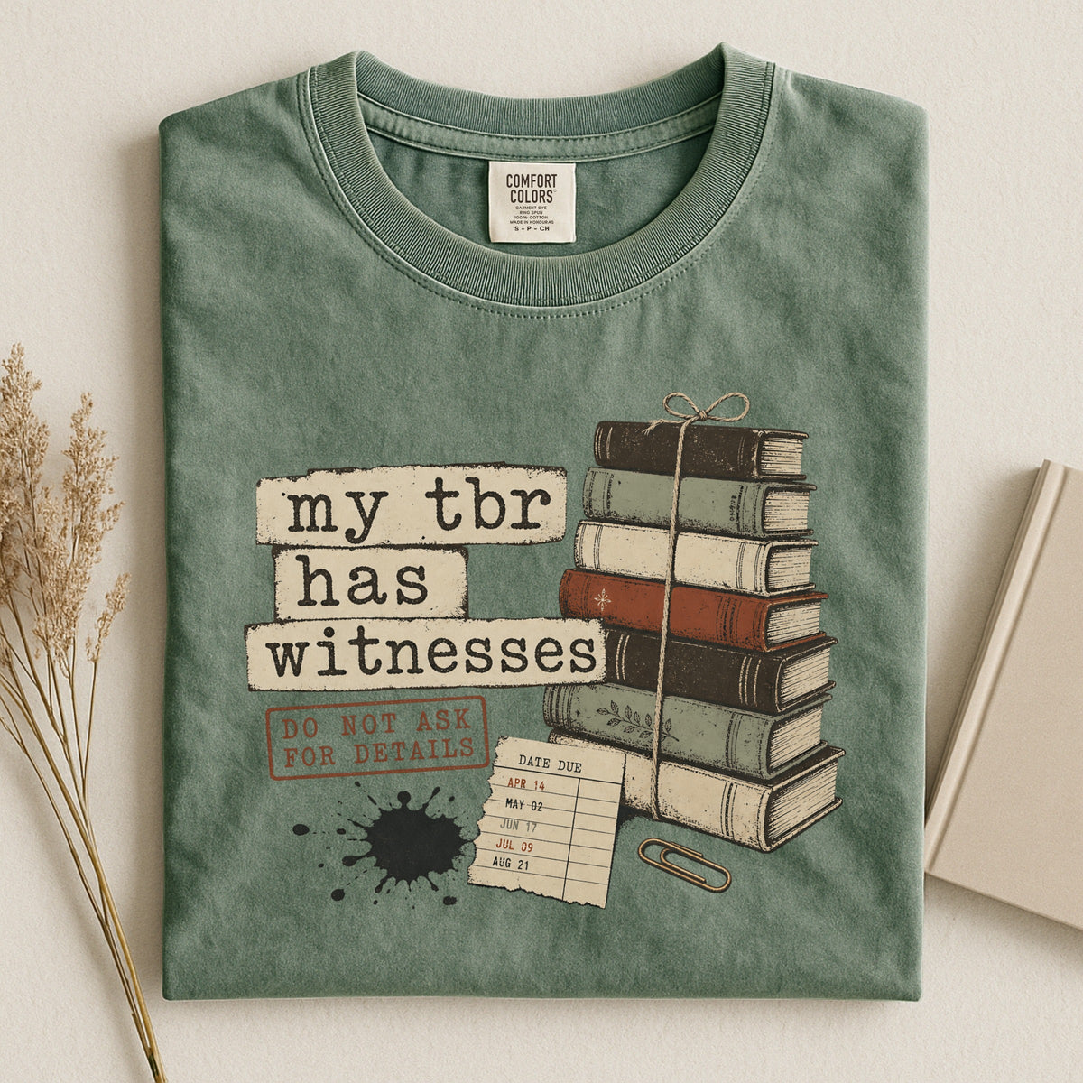 Shelf Love Studio My TBR Has Witnesses t-shirt in Moss, styled flat lay