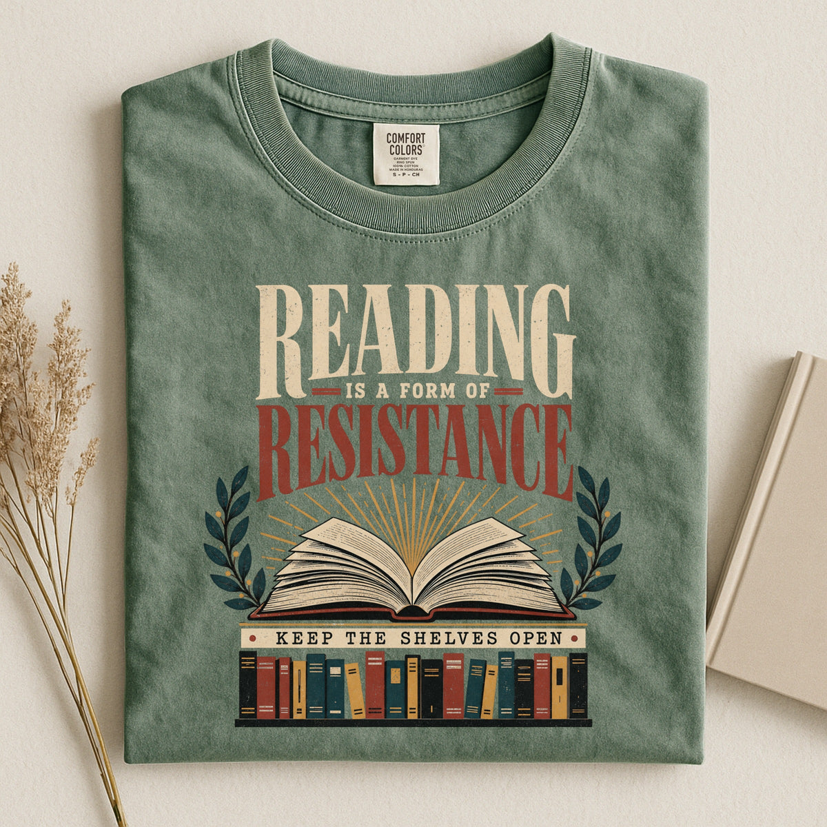 Shelf Love Studio Reading Is a Form of Resistance t-shirt in Moss, styled flat lay