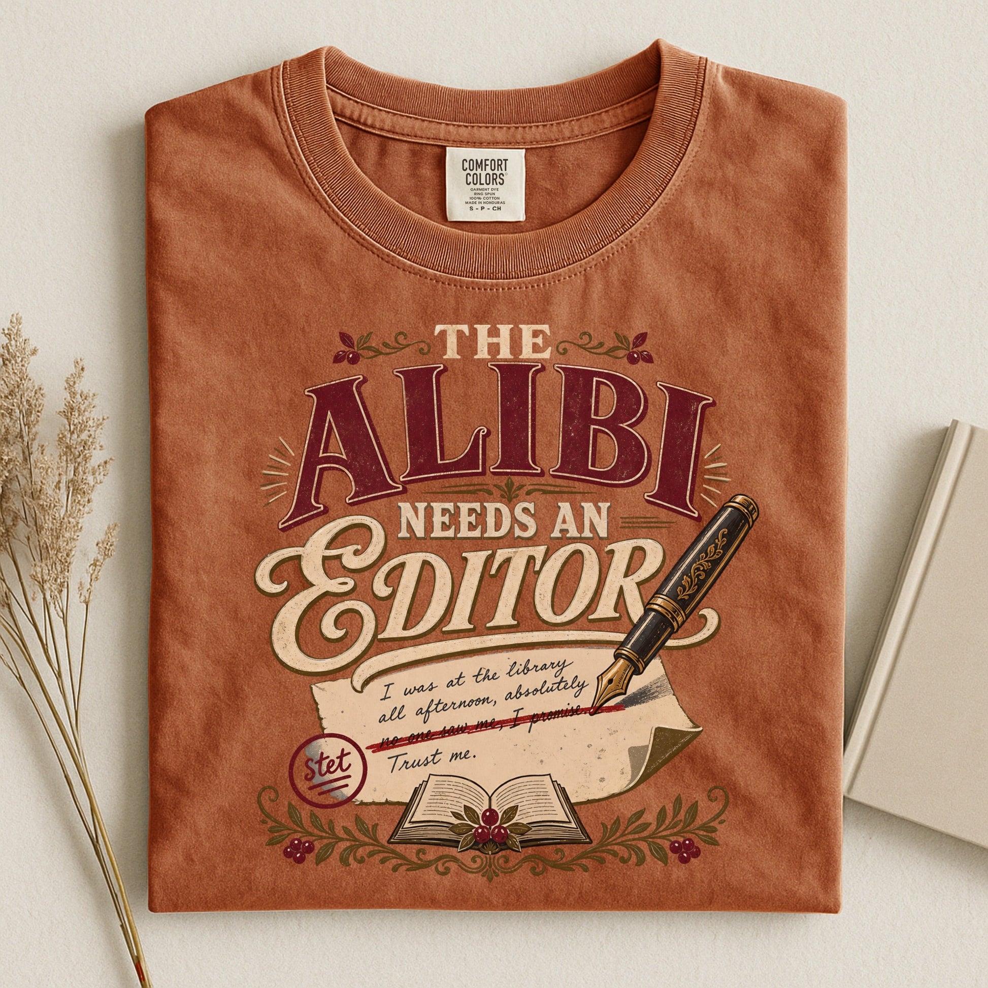 The Alibi Needs an Editor bookish tee in Yam, flat lay